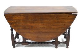 A mahogany oval finished gate leg table on barley twist legs and stretchers,