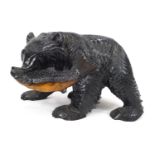 A carved Black Forest style bear with a fish in his mouth, ebonised and painted,