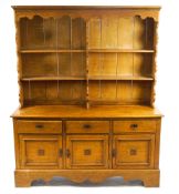 An oak dresser with three cupboards and three drawers, carved leaf detail to doors.