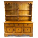 An oak dresser with three cupboards and three drawers, carved leaf detail to doors.