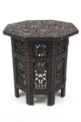 An Indian carved hardwood octagonal collapsible side table on folding stand,