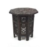 An Indian carved hardwood octagonal collapsible side table on folding stand,