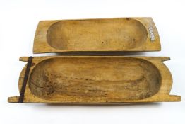 A wooden dough trough with two handled ends and later metal repairs,