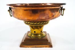 A copper and brass centrepiece, the flat bowl top with turned lip applied with two strap handles,