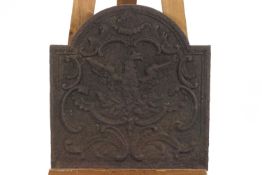 A cast iron fire back with a phoenix and 'C' scrolls,