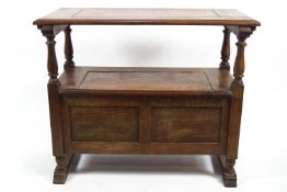 An oak monk's bench with plain rectangular hinged top raised on turned balusters over a blanket box