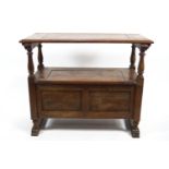 An oak monk's bench with plain rectangular hinged top raised on turned balusters over a blanket box