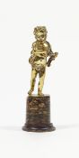 A 19th century cast yellow metal figure of a putto on soapstone base,