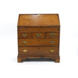 A George III oak bureau with fall front above three short drawers above two long drawers on bracket