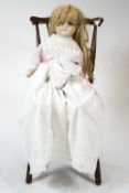 A Victorian wax doll with blue glass eyes, hessian covered body and composition limbs,