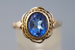 A yellow metal single stone ring, set with an oval blue glass gem, hallmarked 9ct gold, Birmingham.