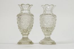 A pair of Regency style cut glass urn shaped vases with panel cut floral flared necks