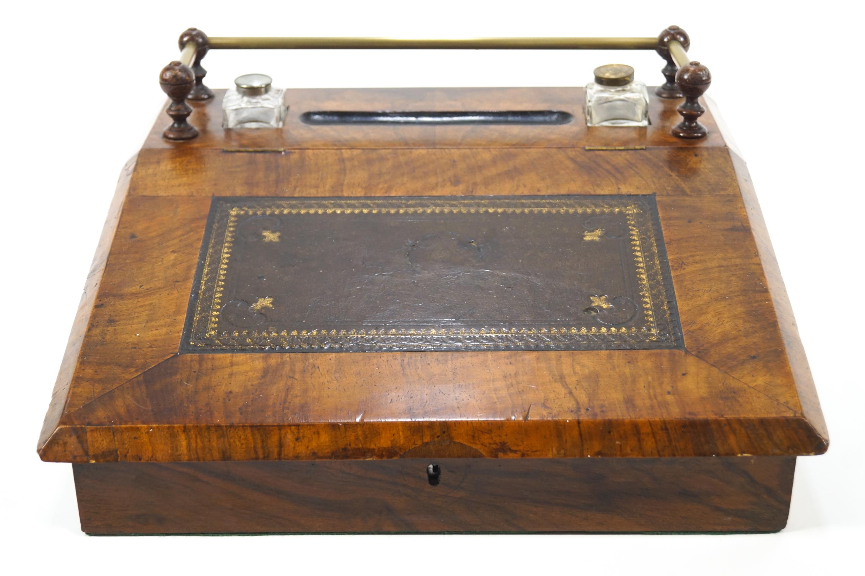 A walnut desk top writing slope with inset embossed leather surface and two ink bottles,