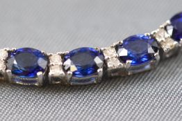 A white metal line bracelet set with twenty six oval faceted cut sapphires