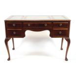 A mahogany writing table with three inset leather skivers over one long and four short drawers