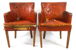 A pair of leather tub shaped chairs on oak tapering legs,