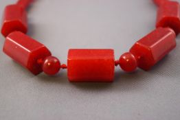 A single strand of graduated red beads, strung knotted with a sterling silver trigger clasp.