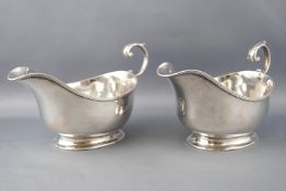 A pair of plain oval form silver sauce boats, with flying S scroll handles raised on plain rim feet,