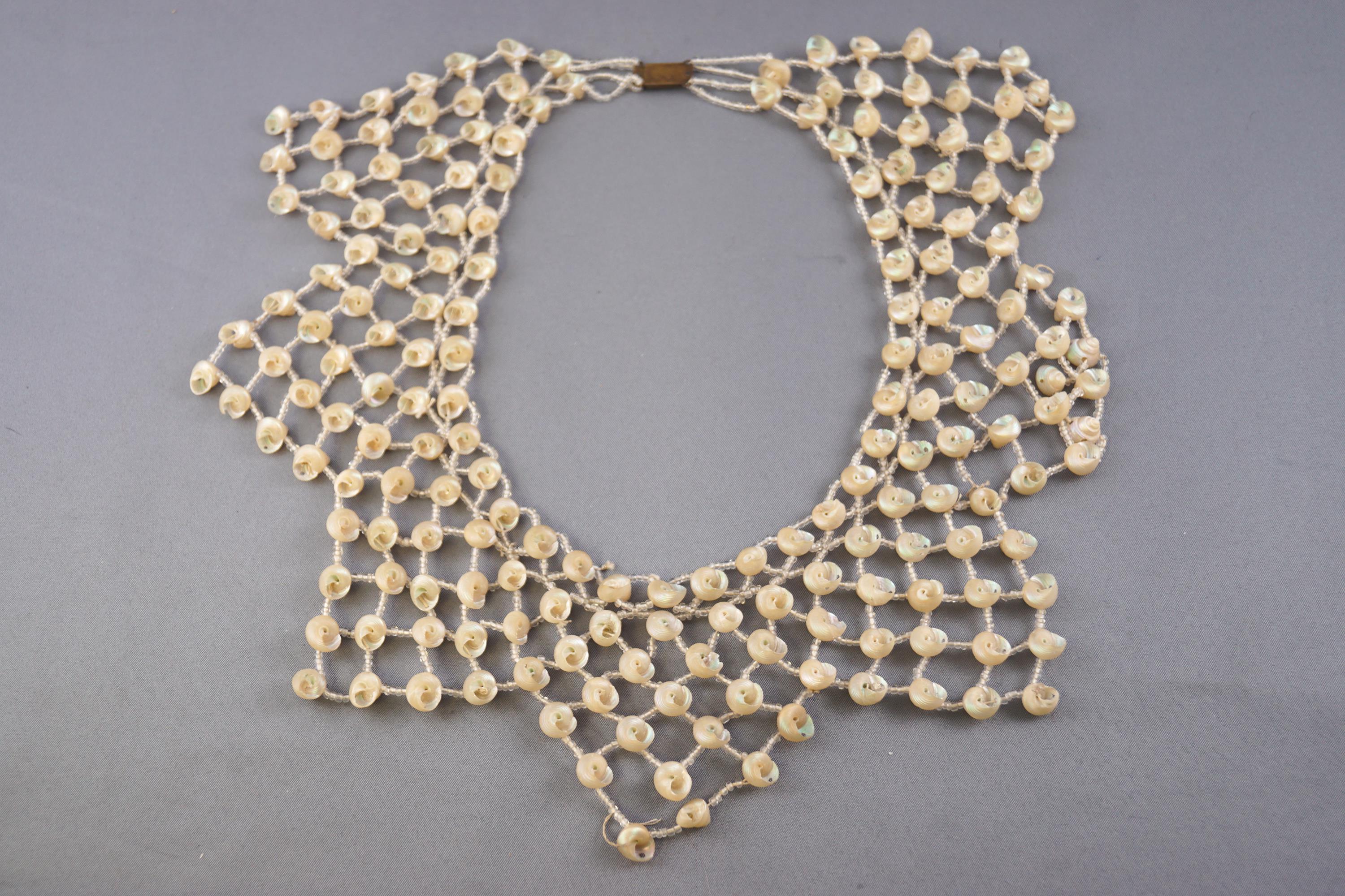 An abstract necklace strung with small shells and inter spaced with colourless seed beads,