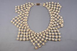 An abstract necklace strung with small shells and inter spaced with colourless seed beads,