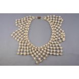 An abstract necklace strung with small shells and inter spaced with colourless seed beads,