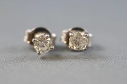 A white metal pair of single stone studs,