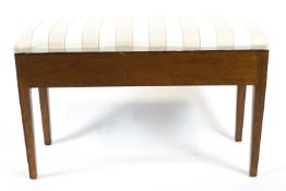 An oak framed piano duet stool with padded seat over a music storage reserve,