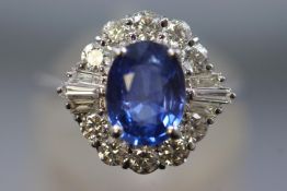 A white metal cluster ring set with a central blue sapphire