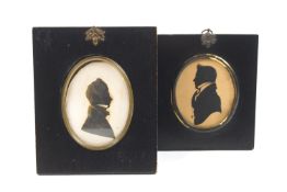 Two highlighted silhouettes of gentlemen in Regency costume in oval brass surrounds