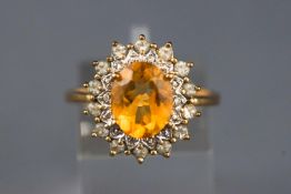 A yellow and white metal cluster ring, set with an oval faceted cut citrine,