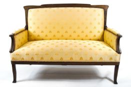 An Arts & Craft style Edwardian mahogany framed settee, upholstered in yellow,