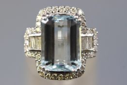 A white metal cluster ring set with a rectangular cut aquamarine