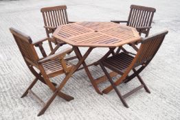 An octagonal slat top teak garden table and four folding chairs