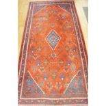 A Hamadan rug, central lozenge on a red ground dotted with geometric motifs, triple band border,