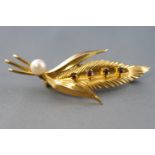 A yellow metal leaf brooch set with four round garnets and finished with a cultured pearl.