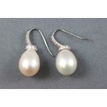 A white metal pair of drop earrings,