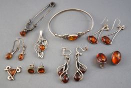 A collection of nine items of amber set silver jewellery.