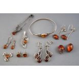 A collection of nine items of amber set silver jewellery.