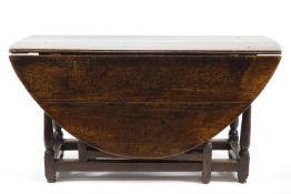 An 18th century oak oval gate leg table on turned legs,