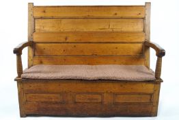 A 19th century predominantly pine settle with double panelled back and two hinged seat panels,