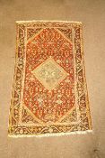 A rug with central medallion on an overall patterned red field within one wide border,