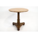 An oak circular occasional table on a triform base,