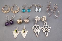 A collection of eight pairs of silver drop earrings of variable designs.