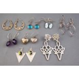 A collection of eight pairs of silver drop earrings of variable designs.