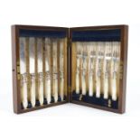 An oak cased set of close plated fruit knives and forks with carved mother of pearl handles,