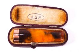 A 9ct gold marked cigar holder, in polished amber, container in a fitted leather case,