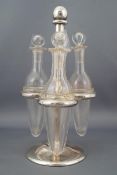 A silver three bottle cruet stand with ring slots for three collared plain glass vials,