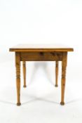 A rectangular pine table with one frieze drawer on turned tapering legs with flared feet,