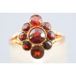 A yellow metal dress ring set with round faceted cut almandine garnets. Stamped 9ct. Size H ½.