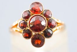 A yellow metal dress ring set with round faceted cut almandine garnets. Stamped 9ct. Size H ½.